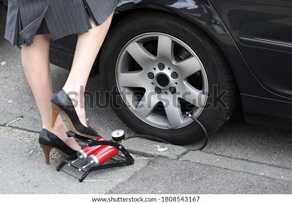 Woman pumping\
a flat tire. Conceptual image\
shot