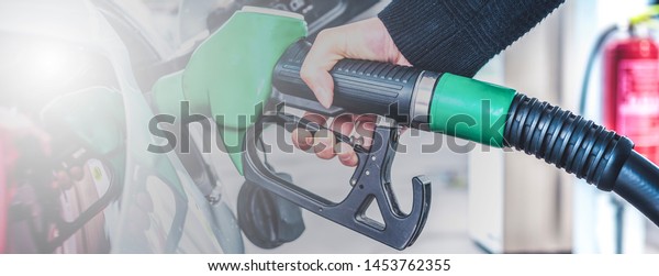 Woman pumping gasoline fuel in car at gas\
station. Panorama