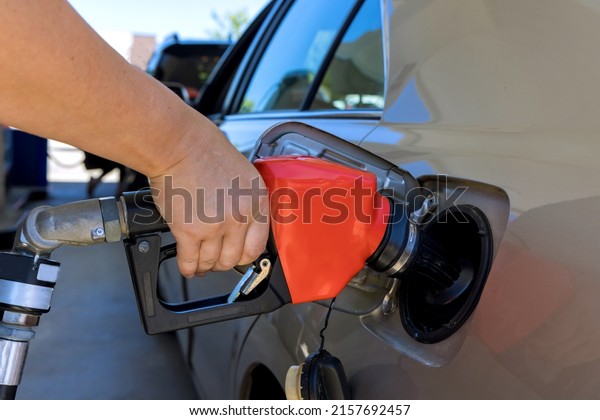 Woman pumping gasoline fuel in car at gas station\
closeup detail