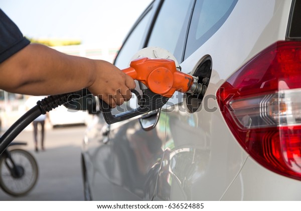   woman pumping gasoline fuel in a car at a gasoline\
station\
 \
