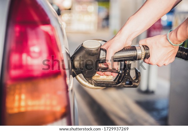 Woman pumping petrol with fuel pump at gas\
station. Petrol price goes down after pandemic coronavirus. high or\
low price of fuel.\
\
