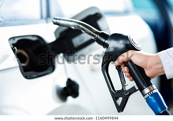 Woman\
pumping petrol at gas station into vehicle. Hand holding a pistol\
or nozzle pump prepare to refuel car with\
gasoline.