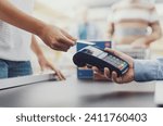 Woman purchasing food at the supermarket and paying with a credit card, the cashier is holding the POS terminal, hands close up