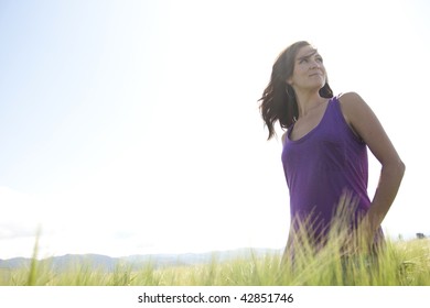 A Woman In A Purple Shirt In A Green Field.