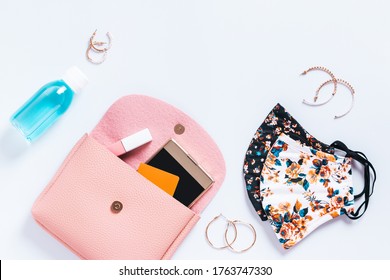 Woman Purse With Fashionable Face Masks, Hand Sanitizer, Smartphone And Cosmetics On White Table Top, New Normal Concept. Stylish Protective Masks And Fashion Accessories, Copy Space