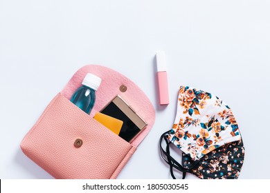 Woman purse with fashionable face masks, hand sanitizer, smartphone and cosmetics on white table top, new normal concept. Stylish protective masks and fashion accessories, copy space - Powered by Shutterstock