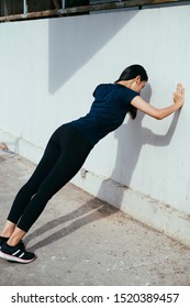 Woman Push Up The Wall Under Sunshine.