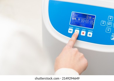 Woman Pushes Button Start On The Centrifuge For Sample Preparation. DNA, Oncology Marker Analysis In Clinical Laboratory.