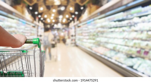 Woman Pushing Shopping Cart With Blur Supermarket Aisle Background