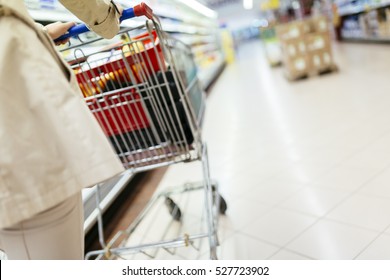 Woman Pushing Shopping Trolley In Supermarket