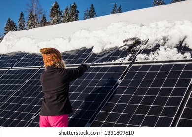 Woman Pushing Snow Off Solar Panels In Winter. If Snow Covers Panels, They Can’t Produce Power. 