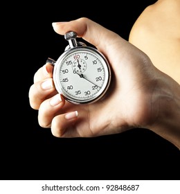 woman pushing stopwatch button against a black background