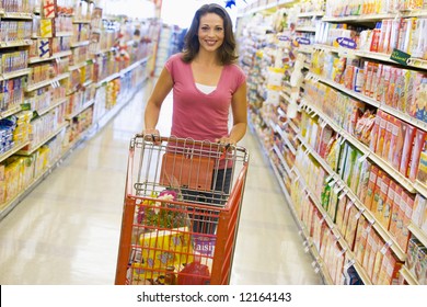 Woman Pushing Trolley Along Supermarket Grocery Aisle