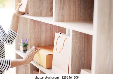 Woman Put A Box In Shelf At Home Office Store.