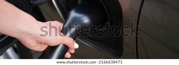 Woman put fuel nozzle on petrol station to refuel\
automobile with diesel