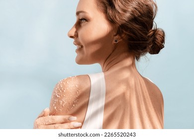 Woman put a natural  white salt scrub to her shoulder 