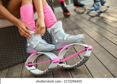 woman put on pink kangoo jumping boots before outdoor fitness workout