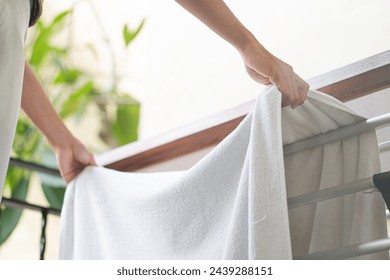 Woman put pure white towel hangs on aluminium hanger clothes rack at balcony - Powered by Shutterstock