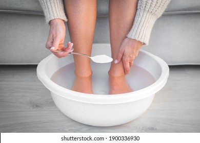 Woman put spoon of baking soda in bath with hot water for her feet. Homemade bath soak for dry feet skin. 