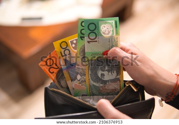 a woman puts Australian dollars in her wallet. A\
woman is holding an Australian currency. A concept showing the\
Australian economy