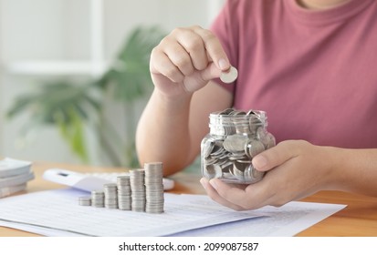 Woman puts a coin dollar in a jar, Saving money for future growth and knowing how to manage your spending wisely, Saving money for business growth or long-term profitability.