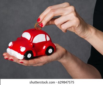 woman puts a coin in a piggy Bank car - Shutterstock ID 629847575