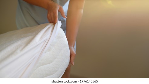 Woman puts a cover on the mattress to protect it from water and house dust mites
