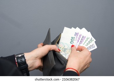 a woman puts Czech crowns in her wallet. The woman holds the Czech currency. A concept showing the Czech economy - Shutterstock ID 2106382067