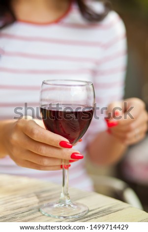 Woman puts glass of red wine in outdoor cafe