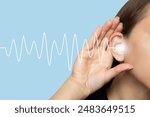 A woman puts her hand to her ear and listens, isolated on a blue background with sound waves. Hearing problems, ear diseases, noise. Concept of testing and hearing loss. Audiometry