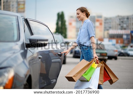 Woman puts her purchases in car on market parking