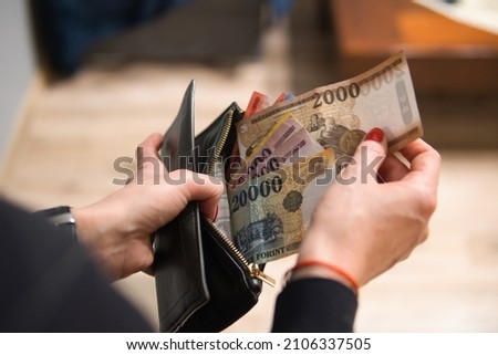 a woman puts Hungarian forints in her wallet. The woman is holding Hungarian money. A concept showing the Hungarian economy