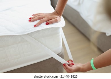 Woman puts mattress topper on mattress. Bed and mattress are covered with topper. Bed laying business concept. - Shutterstock ID 2144041823