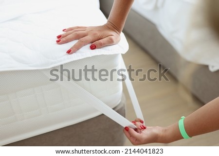 Woman puts mattress topper on mattress. Bed and mattress are covered with topper. Bed laying business concept.