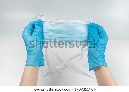 Woman puts on protective mask with blue rubber gloves. Isolated on white.