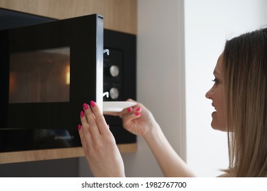 Woman Puts Plate Of Food In Microwave