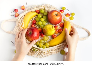 Woman Puts Ripe Fruit In An Eco-friendly Mesh Bag For Shopping. Female Hands Hold A Cotton String Bag With Organic Farm Products. Sustainable Lifestyle.