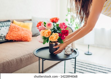 Woman Puts Vase With Flowers Roses On Table. Housewife Taking Care Of Coziness In Apartment. Interior Design And Decor