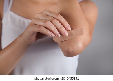 Woman Putting Adhesive Bandage On Arm.