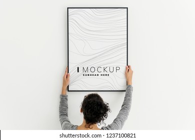 Woman putting up an art piece mockup at home