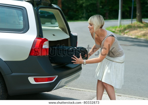 woman putting baggage to car\
trunk