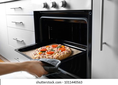 Woman Putting Baking Sheet With Pizza In Oven