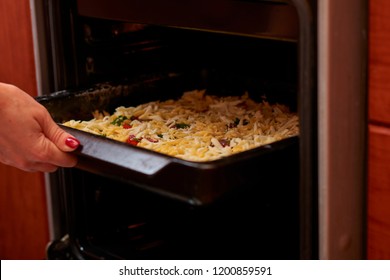 Woman Putting Baking Sheet With Pizza In Oven