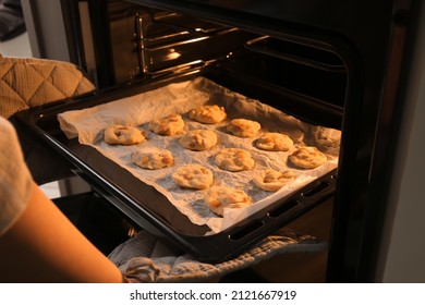 Woman Putting Baking Tray With Homemade Cookies In Oven