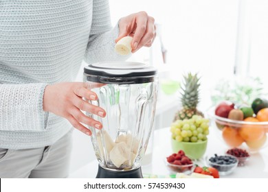 Woman Putting A Banana In A Blender And Preparing A Delicious Healthy Smoothie In Her Kitchen