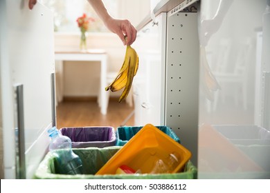 Woman putting banana peel in recycling bio bin in the kitchen. Person in the house kitchen separating waste. Different trash can with colorful garbage bags. - Powered by Shutterstock