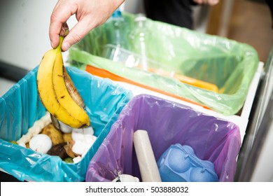 Woman putting banana peel in recycling bio bin in the kitchen. Person in the house kitchen separating waste. Different trash can with colorful garbage bags. - Shutterstock ID 503888032
