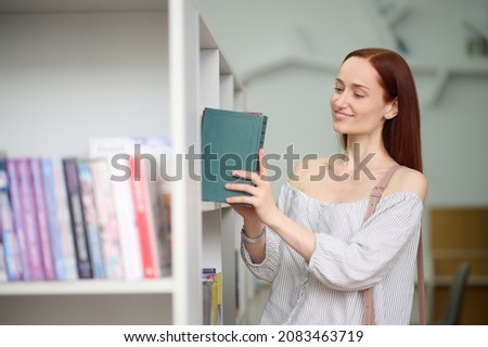 Woman putting book on shelf in library