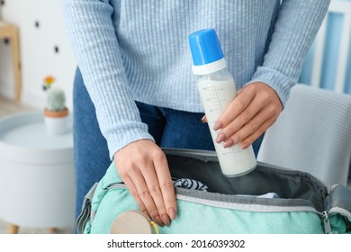 Woman Putting Bottle Of Milk For Baby In Bag At Home