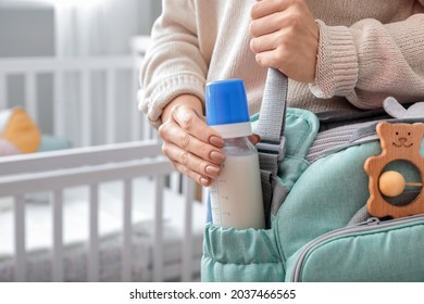 Woman Putting Bottle Of Milk For Baby In Bag At Home